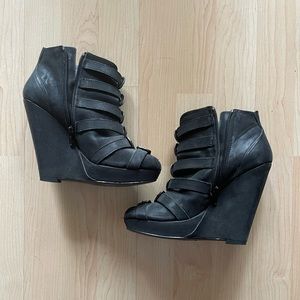 Black leather open toed booties with metal buckles.